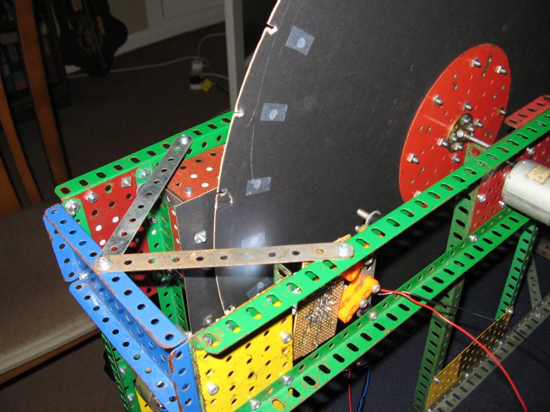 Figure 5 — A member-built NBTV disc televisor, framed in Meccano and photographed mid-construction: the black Nipkow disc, motor, and driver electronics on a breadboard are all visible, wired for the club's 3…