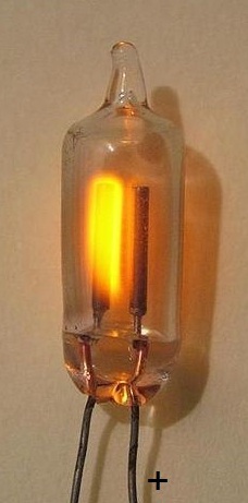 Figure 4 — A neon glow-discharge lamp showing the characteristic orange emission of excited neon gas. Baird Televisors used a larger flat-plate form of this same lamp type, positioned so that the Nipkow disc …
